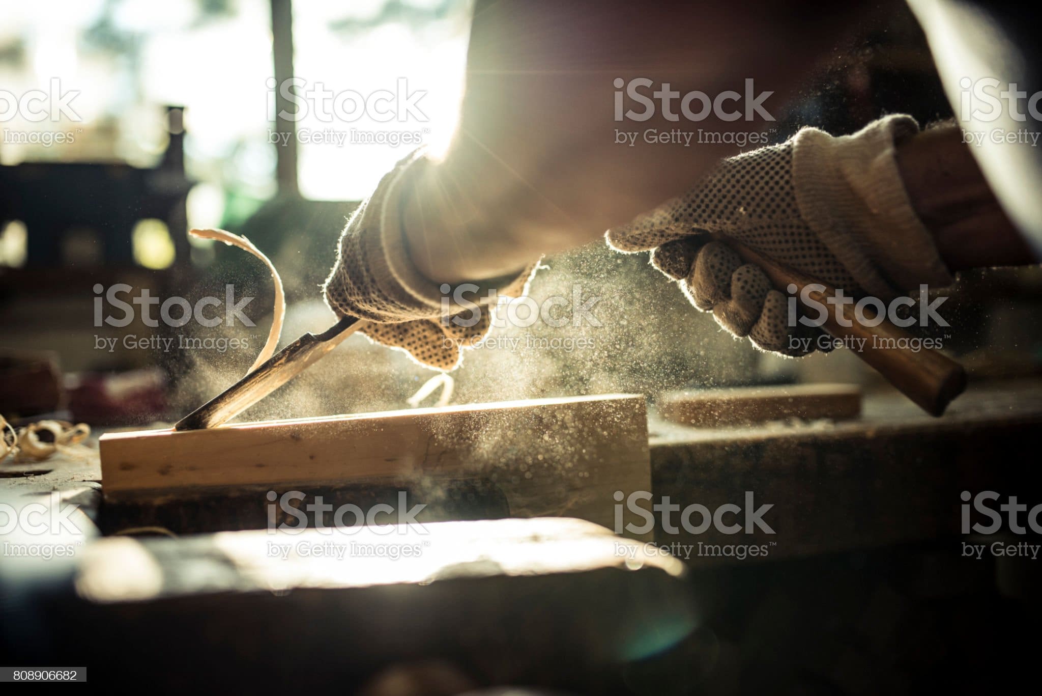 A caucasian senior adult carving wood in a workshop